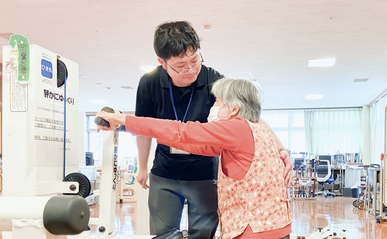 男性介護士と利用者が笑顔でリハビリをしている