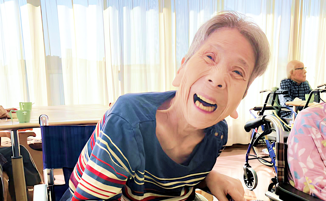 車椅子の女性が笑顔でこちらを見ている