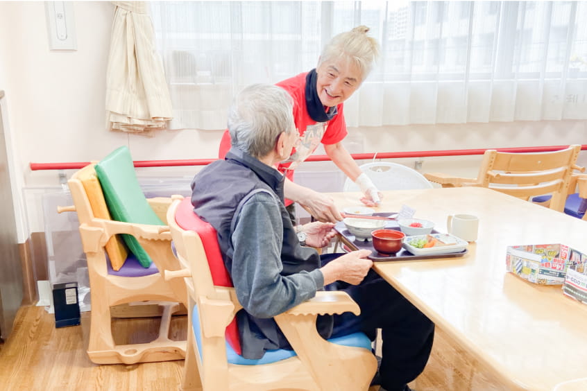 食事を提供する高齢女性と食事を受け取る高齢男性