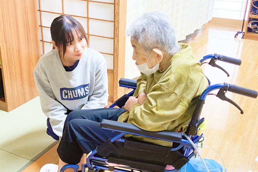 若い女性が車椅子の高齢男性と話す