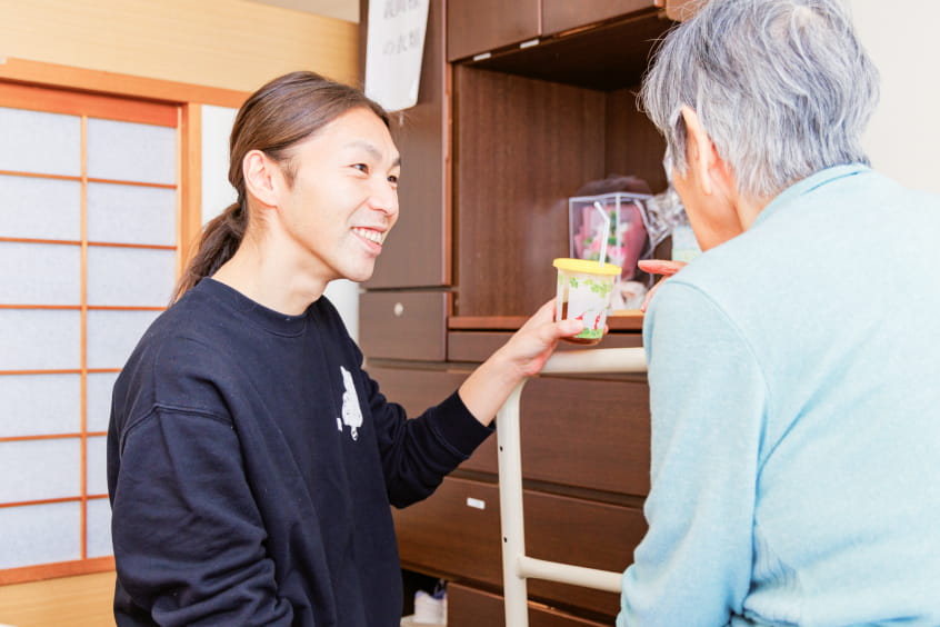 介護士と若者が車椅子の高齢女性を囲む