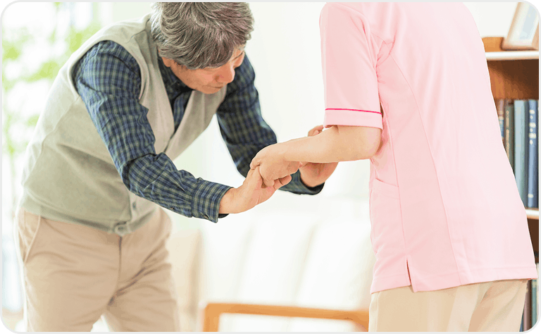 介護士が高齢男性の歩行を補助する